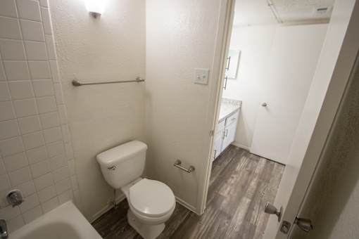 A white toilet in a small bathroom with a white tiled shower.