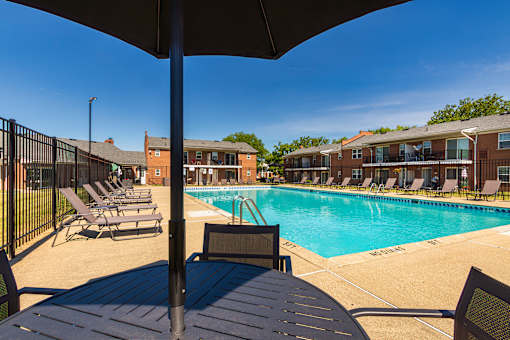 Pool deck seating area with umbrella tables overlooking the community swimming pool