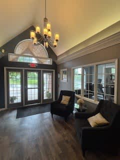 A living room with a black couch and a chandelier.