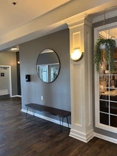 A room with a round mirror and a bench.