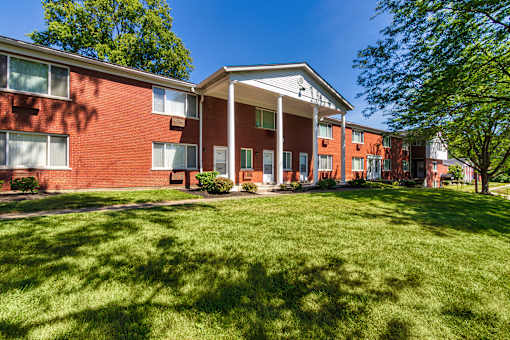 Two-story brick apartment buildings with mature trees and landscaped courtyard