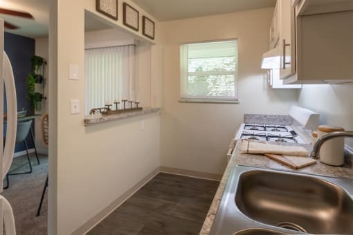 This is a photo of the kitchen with pass through breakfast bar of the 550 square foot 1 bedroom, 1 bath, balcony floor plan model apartment at College Woods Apartments in thne NOrth College Hill neighborhood of Cincinnati, OH.