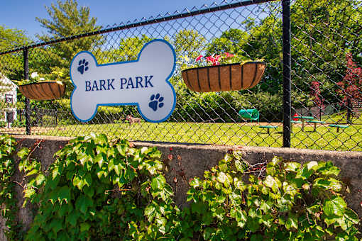 A sign that says Bark Park is hanging on a fence.
