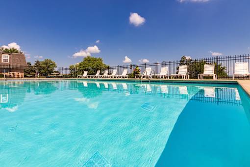A pool surrounded by white lounge chairs at Fairfield Pointe Apartments in Fairfield, Ohio.