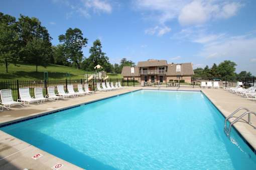 A large swimming pool with white lounge chairs and a building in the background.