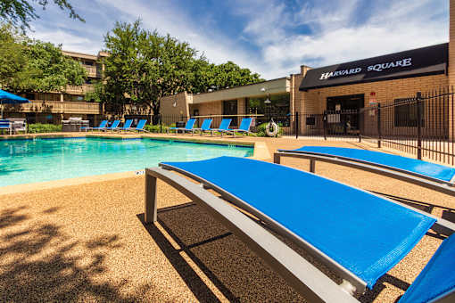 Poolside lounge chairs beside the community swimming pool at Harvard Square Apartments