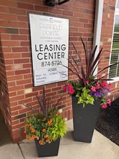 A sign for a leasing center is displayed on a brick wall.