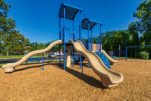 Apartment community playground with slides and open play area at Lisa Ridge Apartments