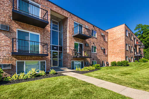 Apartment building exterior with secure entry, balconies, and landscaped lawn at Lisa Ridge Apartments