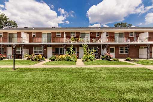 Two-story apartment building with private balcony, landscaped lawn, and central walkway at Lake of the Woods Apartments