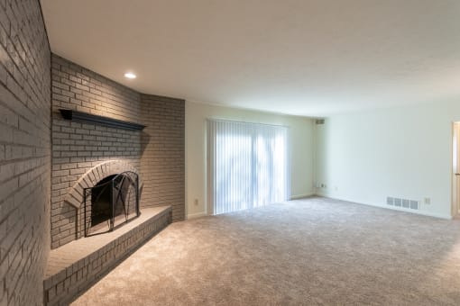 This is a photo the living room with brick wall and wood-burning fireplace of the 925 square foot, Hazelnut 2 bedroom, 1 bath apartment at Montana Valley Apartments in the Westwood neighborhood of Cincinnati, OH.