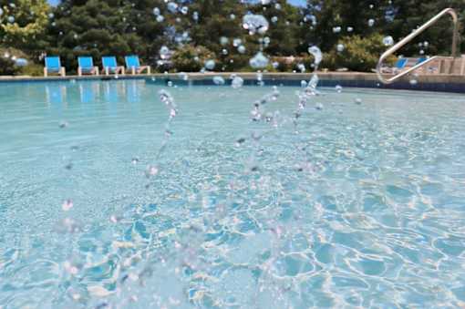 Water splashing in a pool with a ladder in the background.