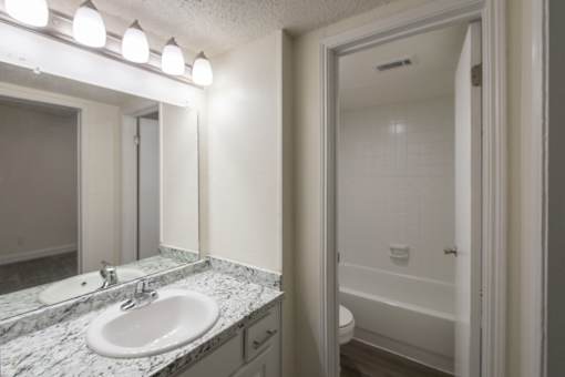 A bathroom with white vanity 1 bedroom, 1 bath apartment home at Princeton Court Apartments in the Vickery Midtown neighborhood of Dallas, TX.