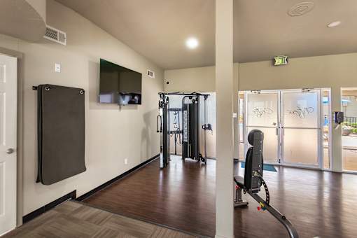 24-hour fitness center with a treadmill, weights and a television at Princeton Court Apartments in the Vickery Midtown neighborhood of Dallas, TX.