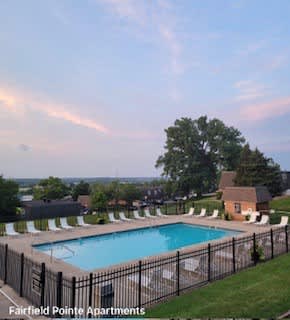 A pool surrounded by a black fence at Fairfield Pointe Apartments.