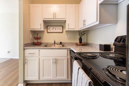 A kitchen with white cabinets and a black stove top.