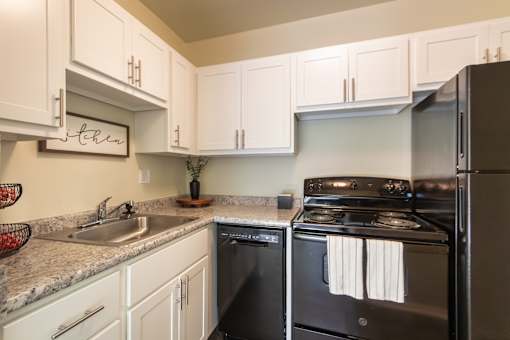 A kitchen with black appliances and white cabinets.