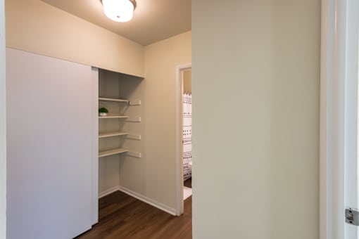A white pantry with a white door and a white fridge.