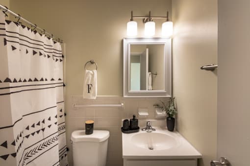 A bathroom with a white sink, toilet, and a mirror above it.