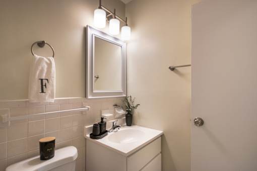 A white bathroom with a towel hung on the wall.