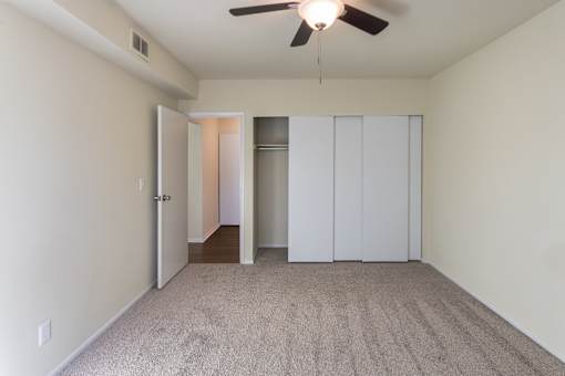 A room with a ceiling fan and carpeted floor.