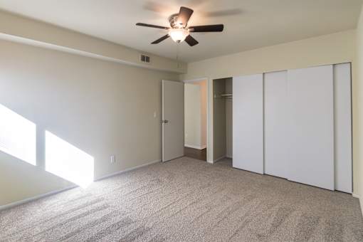 A room with a ceiling fan and carpeted floor.