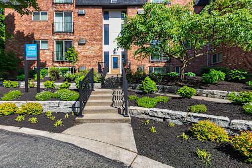Apartment building with entrance to the leasing office and the blue leasing office sign at Romaine Court Apartments in the Oakley neighborhood of Cincinnati, Ohio.