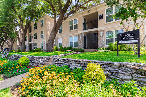 Building exterior and sign directing to the leasing office at The Summit at Midtown Apartments in Midtown, Dallas, TX.