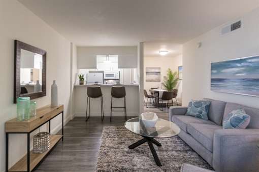 A modern living room with a grey sofa and a glass coffee table in the 558 square foot 1 bedroom, 1 bath model apartment at The Summit at Midtown Apartments in the Dallas Midtown neighborhood of Dallas, TX.
