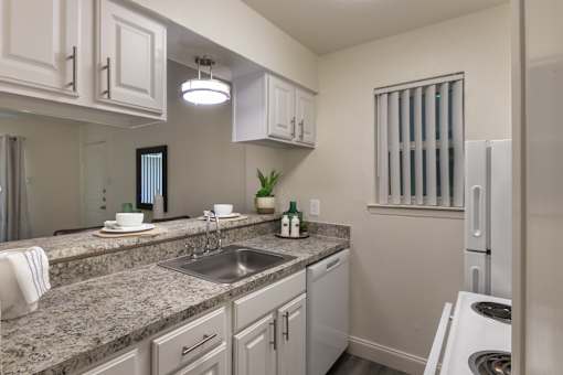 Kitchen with white cabinetry, granite-style countertops, double sink, and breakfast bar in the 558-square-foot 1 Bedroom, 1 Bath A at The Summit at Midtown