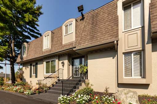 Leasing office exterior with front steps, flower beds, and landscaped entry at Village East Apartments