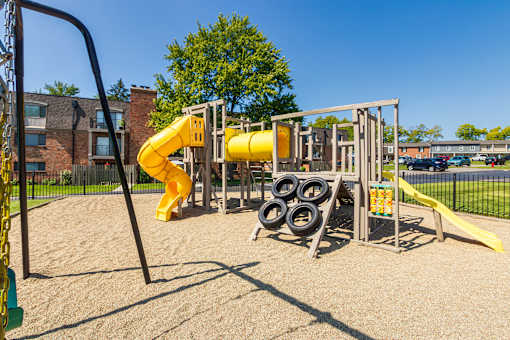 Community playground with slides, swings, and safety surface at Village East Apartments