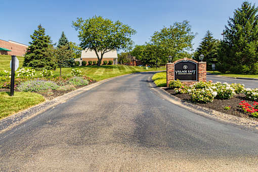Landscaped entrance drive with monument sign at Village East Apartments in Franklin, Ohio