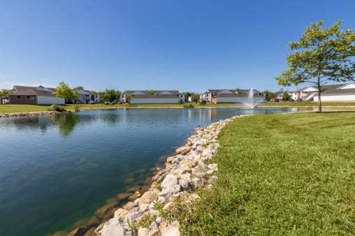 This is a photo of a pond with a fountain and building exteriors at Washington Place Apartments in Miamisburg, Ohio in Washington Township.