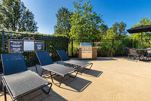 A sunny day at the pool with chairs and a signboard.