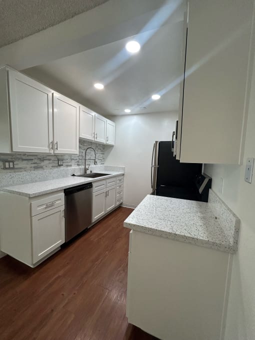 an empty kitchen with white cabinets and a counter top at Copa Ladeene Apartments, Torrance California