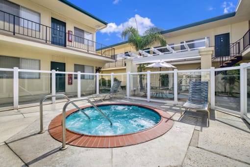 a jacuzzi in the middle of a pool in front of a building at Olive Tree Apartments, Torrance, CA