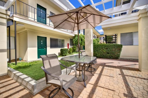 a patio with an umbrella and a table with chairs at Olive Tree Apartments, Torrance, CA 90503
