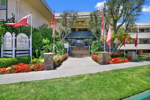 the front of a building with flags and a sidewalk at Camino de Oro Apartments, Torrance, CA