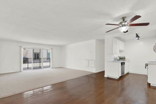 an empty living room with a ceiling fan and a kitchen at Camino de Oro Apartments, Torrance, California