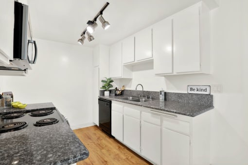 a kitchen with white cabinets and granite counter tops at Casa Del Amo Apartments, Torrance, 90505