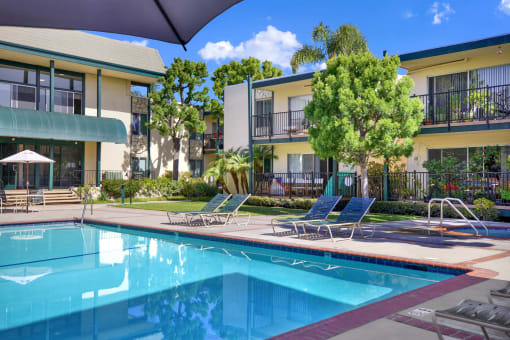 a swimming pool in front of an apartment building at Copa Ladeene Apartments, Torrance
