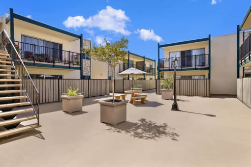 a courtyard with tables and chairs and stairs at Copa Ladeene Apartments, California, 90505