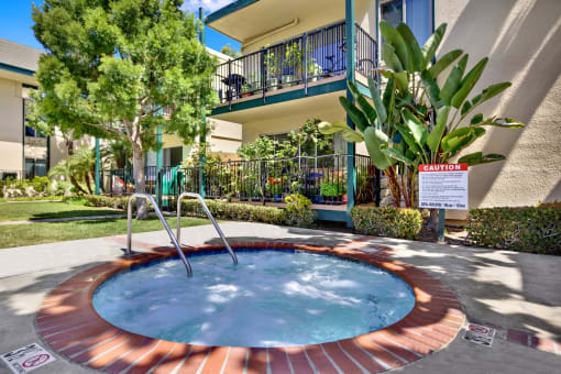 a jacuzzi in the yard of a house with a building in the at Copa Ladeene Apartments, Torrance, CA