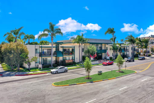 a building with palm trees and cars parked in front of it at Copa Ladeene Apartments, Torrance, 90505