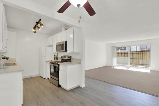 an empty living room with a kitchen and a ceiling fan at Copa Ladeene Apartments, California