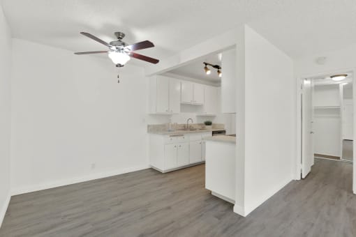 an empty living room and kitchen with a ceiling fan at Copa Ladeene Apartments, Torrance