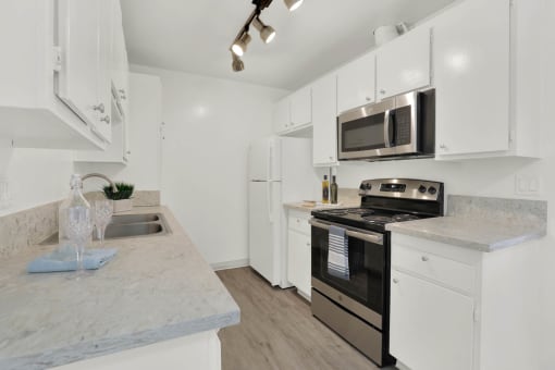 a kitchen with white cabinets and stainless steel appliances at Copa Ladeene Apartments, California, 90505