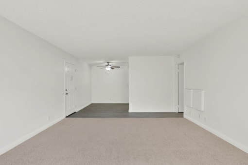 an empty living room with white walls and a ceiling fan at Copa Ladeene Apartments, California