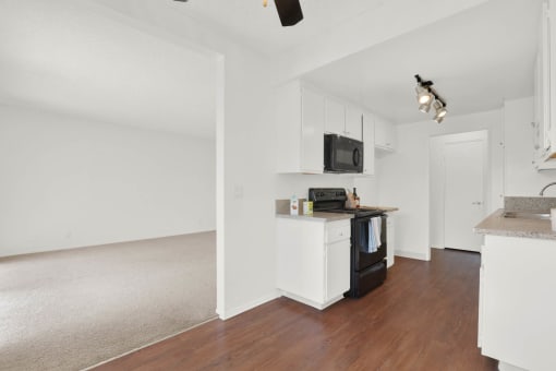 a kitchen with white cabinets and a black stove at Copa Ladeene Apartments, Torrance, CA 90505